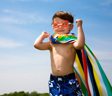 young boy wearing towel as cape and swimming goggles