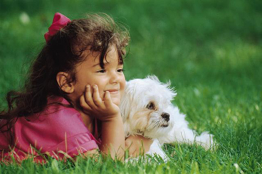three year old girl on lawn with puppy