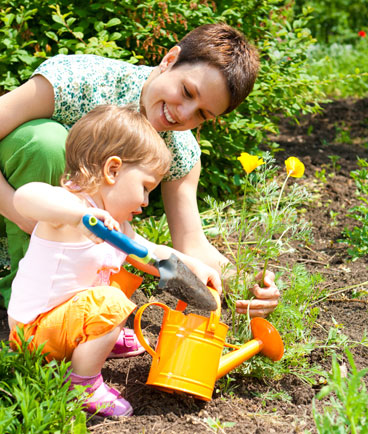 toddler girl helping mom plant flowers