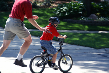 dad teaching a preschooler ride a bike